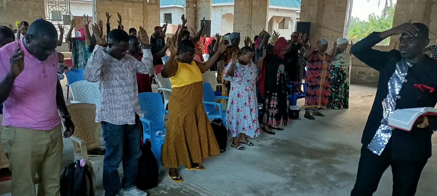 A congregation worshipping together in an open community hall