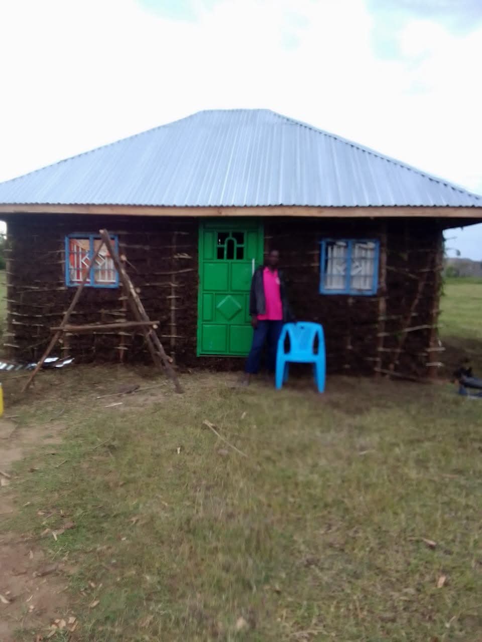 A rural home with a metal roof and a resident standing at the doorway