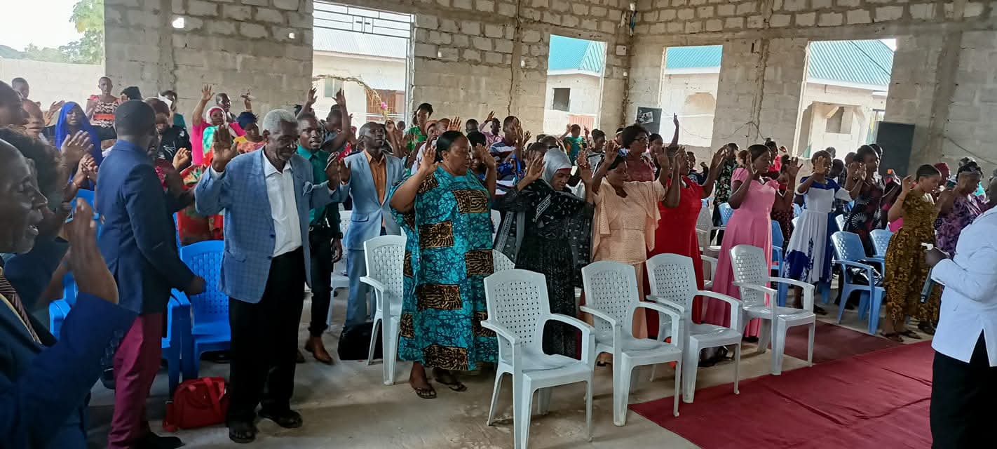 A congregation worshipping inside an unfinished church building